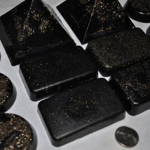 May include: A collection of black, rectangular, and pyramid-shaped objects with a glittery, textured surface.