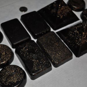 May include: A collection of black pyramid-shaped and rectangular objects with gold glitter embedded in the surface.