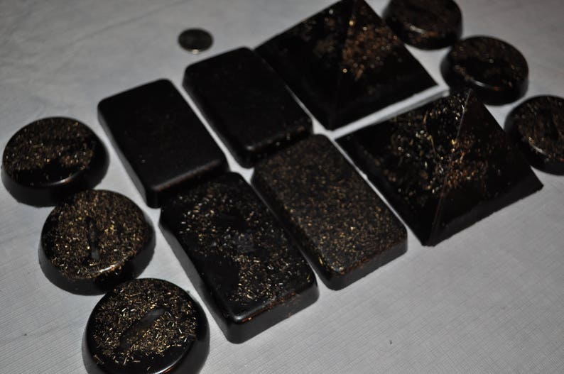 May include: A collection of black pyramid-shaped and rectangular objects with gold glitter embedded in the surface.