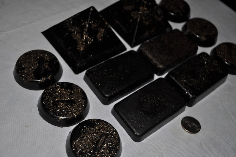 May include: A collection of black and gold coasters with a variety of geometric shapes and designs. The coasters are made of a smooth, polished material and have a subtle shimmer.