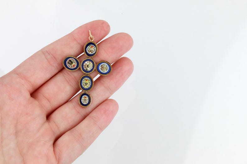 May include: A gold cross pendant with blue enamel and colourful mosaic details. The cross is made up of seven round pieces, each with a different design.