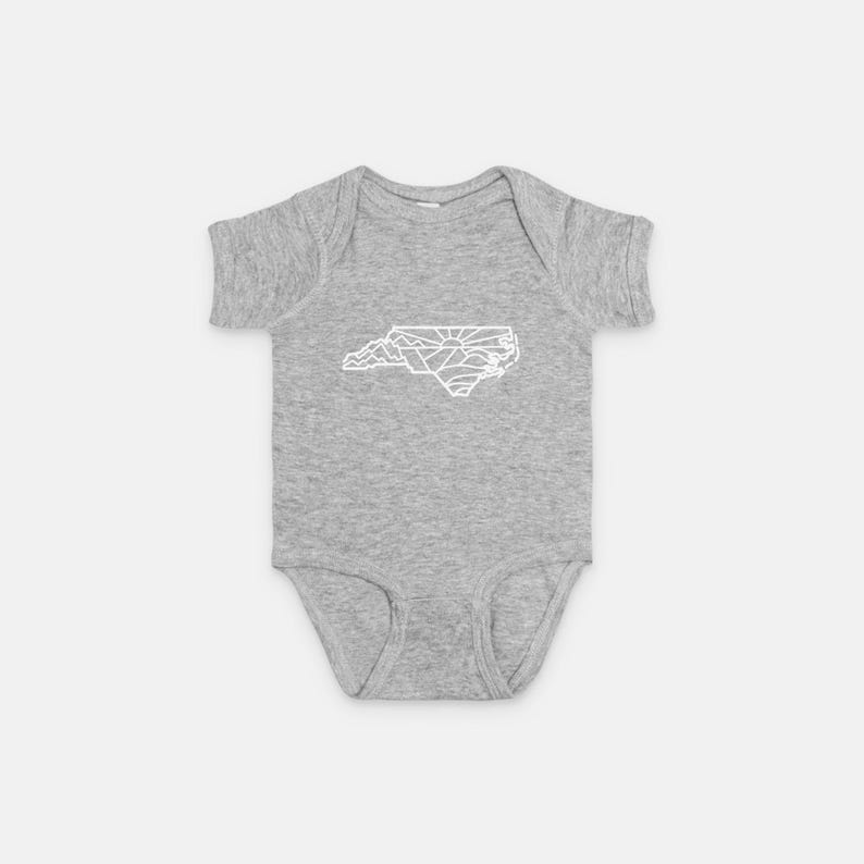 May include: A gray baby onesie with a white outline of the state of North Carolina.