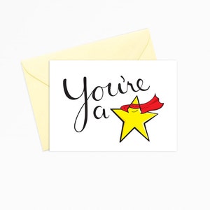May include: A white card with black text that reads "You're a star" with a yellow star wearing a red cape.
