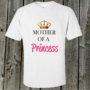 以下が含まれることがあります： 金色の王冠と「プリンセスの母」という文字が黒とピンクで書かれた白いTシャツです。