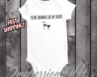 Puede incluir: Un body blanco para bebé con el texto "Future Drummer Like My Daddy!" y una ilustración en blanco y negro de una batería.