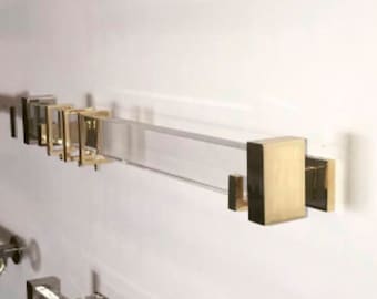 May include: A display of various curtain rods mounted on a white wall. The rods feature diverse designs, including clear acrylic, brushed metal, and gold finishes. The rods are of varying lengths and styles, showcasing a range of decorative options.