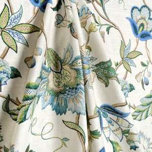 May include: A white fabric with a blue, green, and brown floral pattern. The fabric has a subtle sheen and a soft texture.
