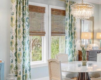 May include: A dining room with patterned curtains in shades of green, blue, and yellow. The room features a round marble table, ornate chairs, and a crystal chandelier. Woven bamboo shades cover the windows.