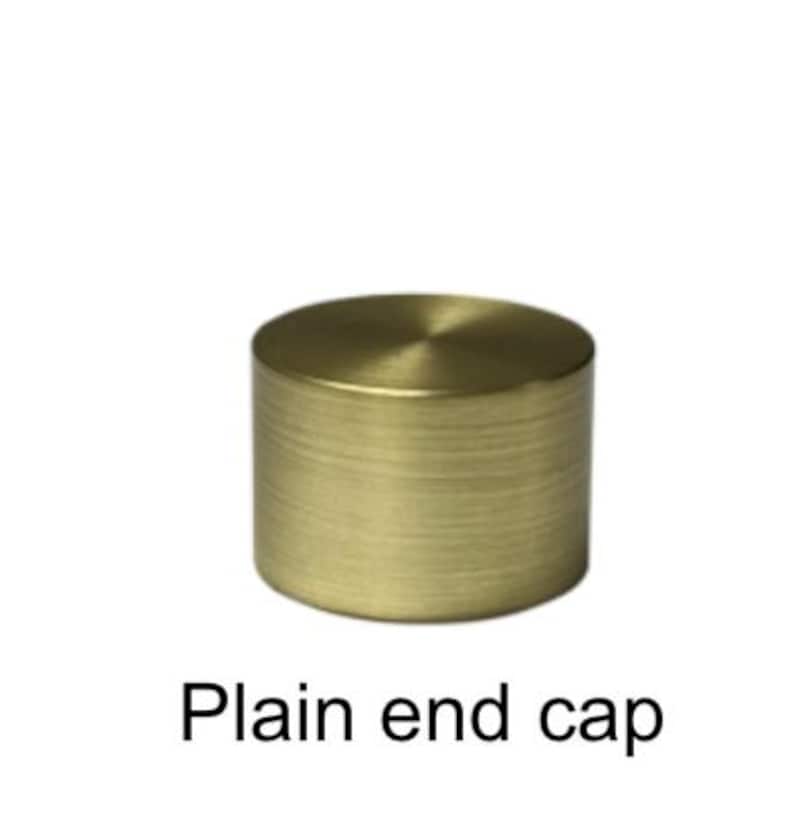 Pu&ograve; includere: Un tappo terminale cilindrico in ottone dorato con una parte superiore piatta e un corpo strutturato e scanalato. Il tappo &egrave; di colore oro caldo ed &egrave; posto su uno sfondo bianco. Il testo "Plain end cap" &egrave; sotto.