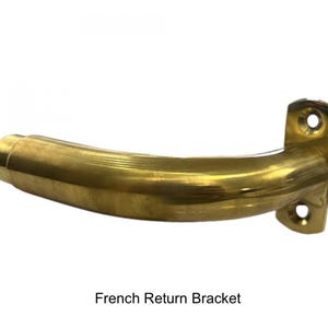 Pu&ograve; includere: Una staffa di ritorno francese in ottone con un design curvo. La staffa ha una piastra di montaggio rettangolare con due fori per le viti e un braccio curvo. Il testo "French Return Bracket" &egrave; sotto.