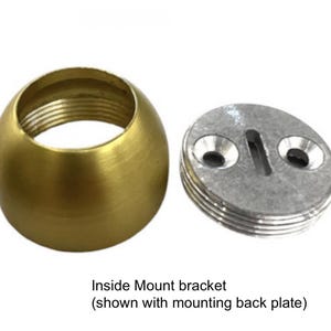 Pu&ograve; includere: Un componente sferico filettato color ottone accanto a una piastra posteriore di montaggio ovale color argento. La piastra posteriore ha due fori e una fessura. Il testo "Inside Mount bracket" &egrave; sotto.