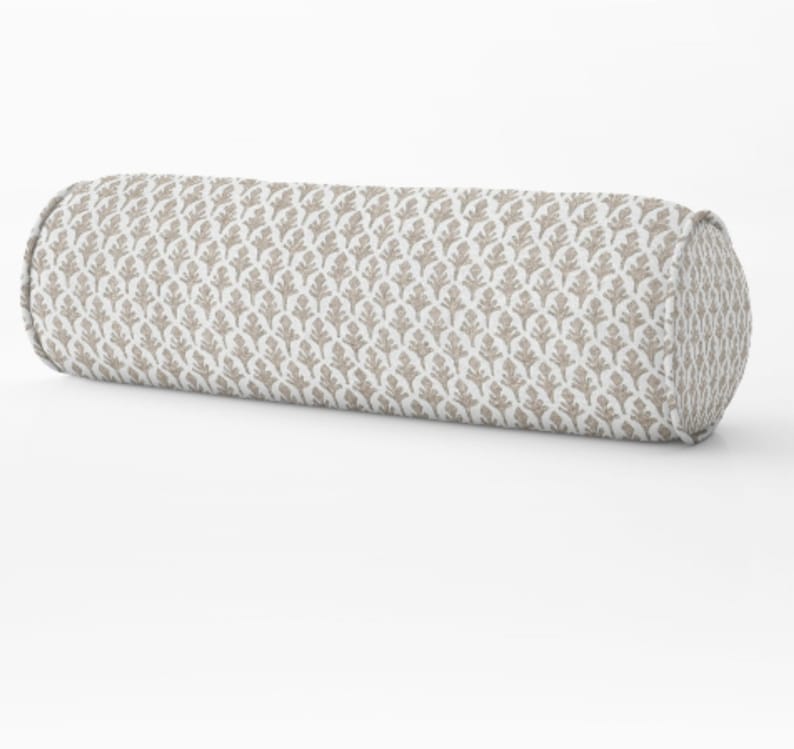 May include: A cylindrical bolster pillow with a repeating pattern of taupe-colored leaf shapes on a white background. The ends of the pillow are rounded and the fabric has a textured appearance. This decorative pillow is designed for comfort and style.