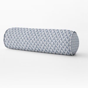 Puede incluir: Un cojín de apoyo azul y blanco con estampado. El cojín es cilíndrico y tiene un fondo blanco con un estampado floral azul repetido.