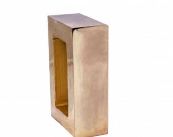 May include: A rectangular, gold-colored metal decorative object with a hollow center. The object has a smooth, reflective surface and a boxy shape. The interior of the object appears to be a lighter shade of gold.