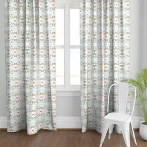 Puede incluir: Dos cortinas blancas con un patrón geométrico en tonos de verde, azul y rosa. Las cortinas están colgadas en una ventana con un marco blanco.