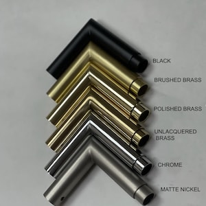 Pu&ograve; includere: Campioni di telai metallici angolari in varie finiture: nero, ottone spazzolato, ottone lucido, ottone non verniciato, cromo e nichel opaco. Ogni campione &egrave; etichettato con il suo nome di finitura. I telai sono disposti in pila diagonale.