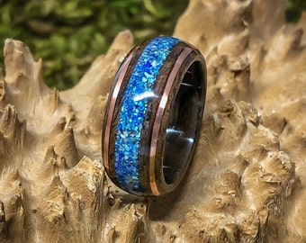May include: A dark wood ring with a blue and copper inlay. The ring is made of wood and metal and has a unique design.