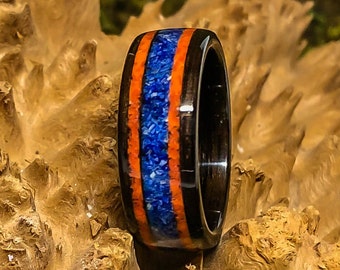 May include: A black wood ring with a blue and orange inlay. The ring is made of wood and has a polished finish.