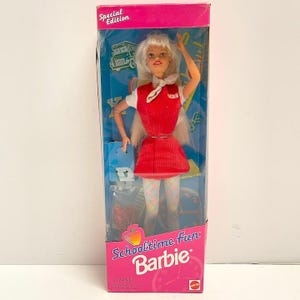 May include: A vintage Barbie doll in its original packaging. The doll is dressed in a red school uniform with a white collar and has blonde hair. The packaging is pink and blue with the text "Schooltime Fun Barbie" and "Special Edition".