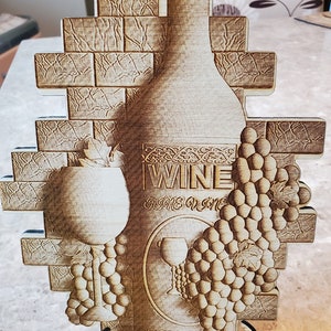 May include: A wooden wine bottle holder with a brick wall design. The holder features a wine bottle, a wine glass, and grapes. The text "WINE" is engraved on the bottle.