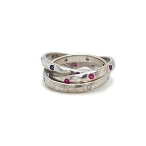 May include: A silver ring with three interlocking bands, each set with small pink and purple gemstones.