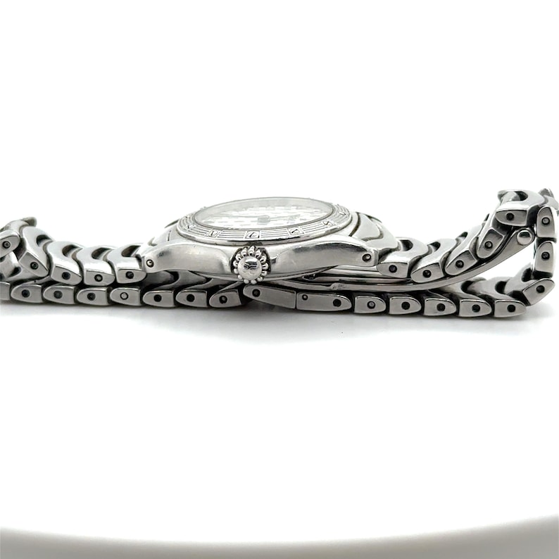 May include: A silver wristwatch with a silver metal band. The watch has a white face with black markings and a silver bezel.