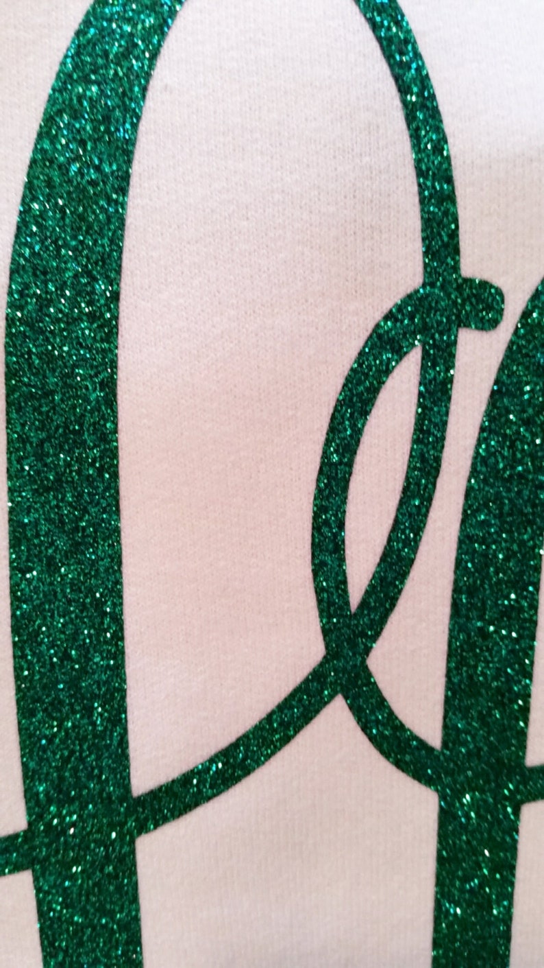 May include: Close-up of a green glitter "Peace" sign on a white background.