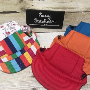 Puede incluir: Cuatro sombreros de perro de tela diferentes. Los sombreros son de varios colores y patrones, incluyendo floral, a rayas, naranja y rojo. Los sombreros est&aacute;n hechos de una tela suave y c&oacute;moda y son perfectos para mantener las orejas de tu perro calientes y protegidas del sol.