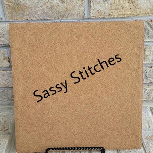 May include: A corkboard with the text "Sassy Stitches" printed in black on a brown background.