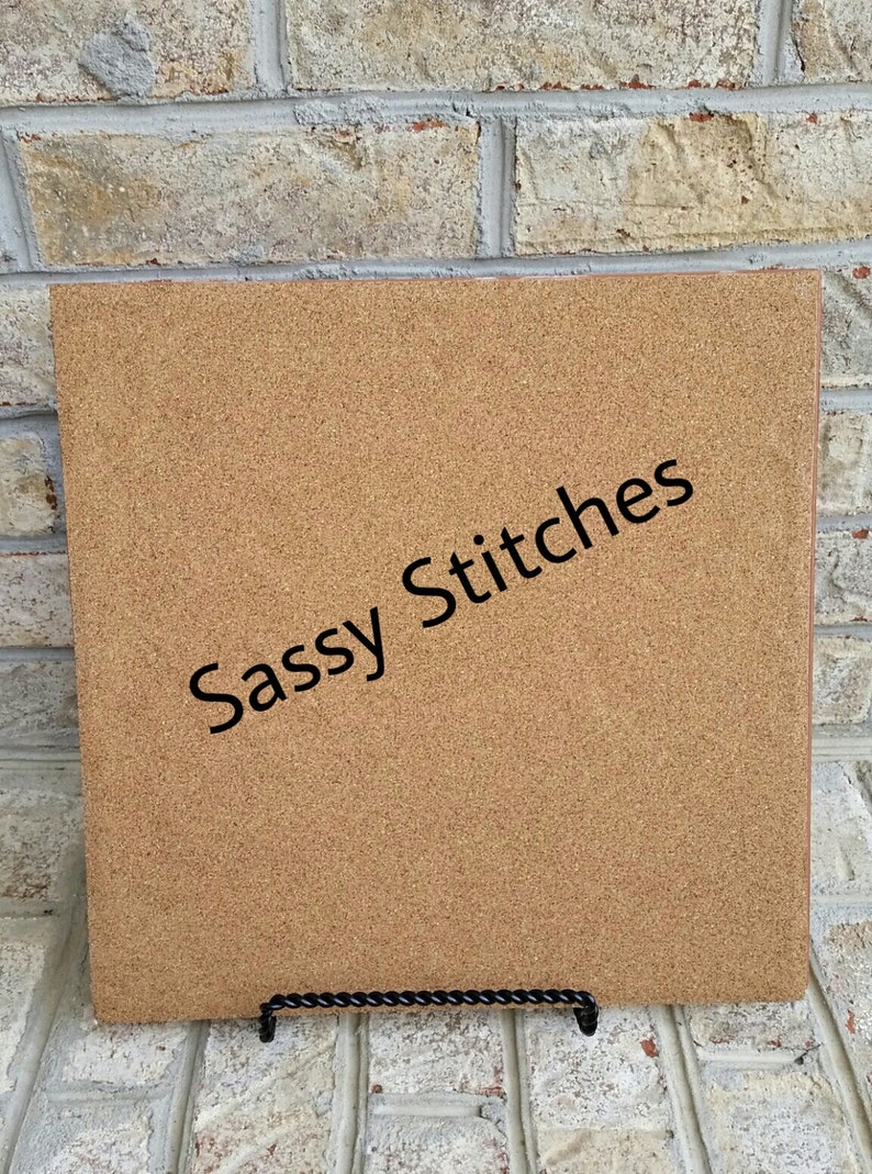 May include: A corkboard with the text "Sassy Stitches" printed in black on a brown background.