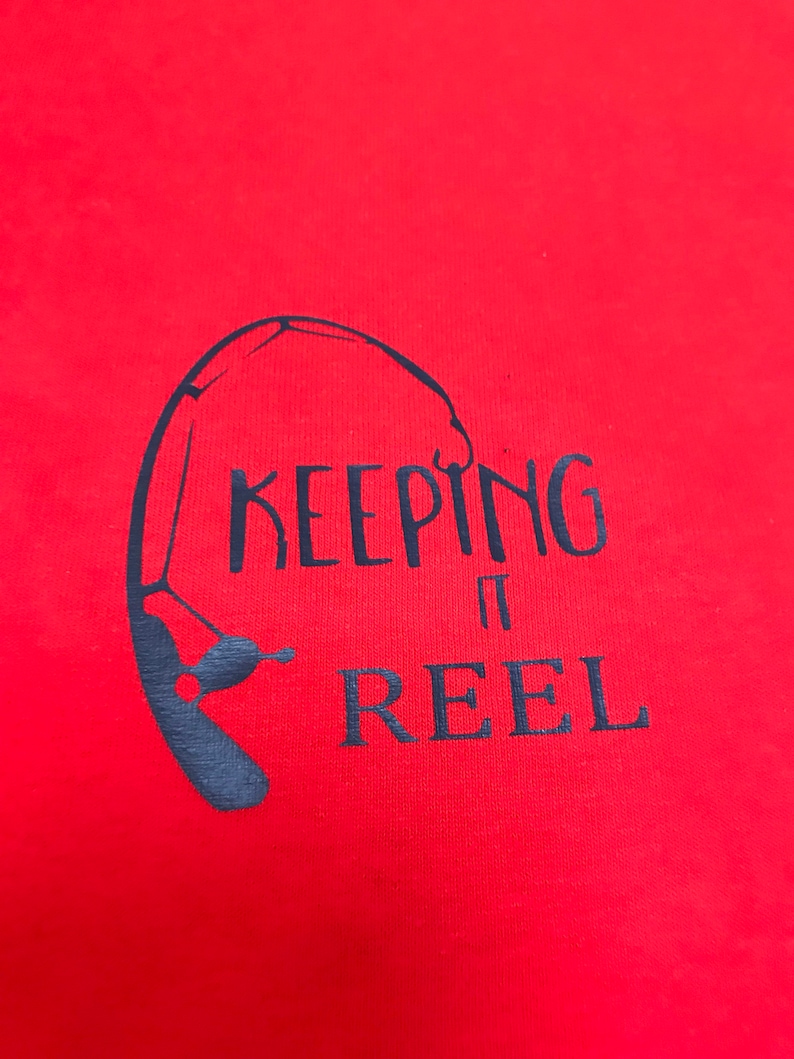 May include: Red t-shirt with a black graphic of a fishing rod and the text "KEEPING IT REEL".