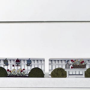 May include: Two decorative wooden fence scenes. One features birdhouses with the words "Home" and "Sweet Home", and colorful flowers. The other scene has a watering can, a basket of flowers, and two green bushes. The scenes are on a white background.