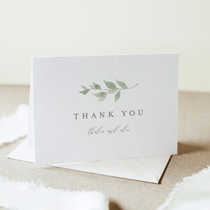 May include: A white thank you card with a simple green watercolor leaf branch design. The text "THANK YOU" is printed in black and the names "Thalia and Alex" are printed in gray.