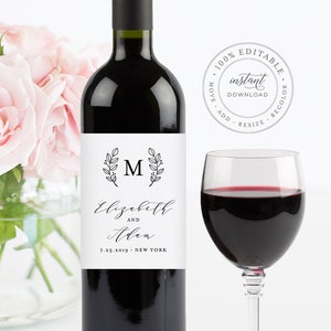 May include: A printable wine bottle label with a black and white design. The label features a floral wreath with the letter "M" in the centre. The text "Elizabeth and Adam" is written in cursive script below the wreath. The date "7.23.2019" and the location "NEW YORK" are printed below the names.
