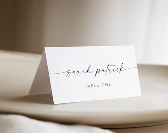 May include: White table card with black calligraphy that reads "sarah patrick" and "TABLE ONE".