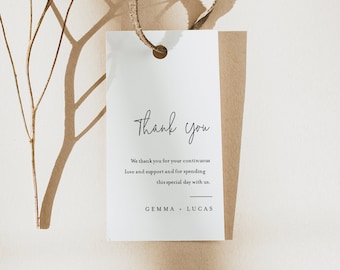 May include: A white thank you tag with a brown string attached. The tag has the text "Thank you" in a handwritten font. The text below reads "We thank you for your continuous love and support and for spending this special day with us. GEMMA + LUCAS". The tag is on a brown background.