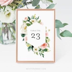 May include: White and pink floral table number card with a hexagon frame and the text "TABLE NO. 23".