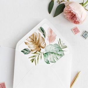 May include: A white envelope with a tropical leaf design liner. The liner features brown, green, and pink leaves. The envelope is lying flat on a white surface with a gold pen and a wax seal.