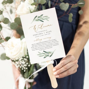May include: A white wedding ceremony program fan with a green olive branch design. The text reads "Welcome to the wedding of Chelsea + Alex August 14, 2010 New York Wedding Ceremony".