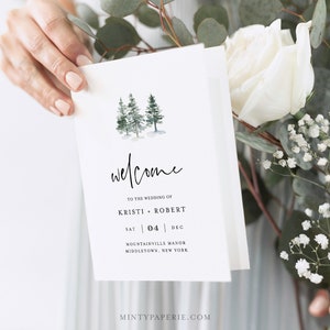 以下が含まれることがあります： 3本の松の木の水彩画が描かれた結婚式用のウェルカムサイン。テキストには「ようこそ」と、Kristi + Robertの結婚式、土 12月4日、Mountainville Manor、ミドルタウン、ニューヨークと記載されています。