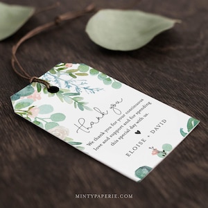 May include: A white thank you tag with a watercolor floral design in shades of green and pink. The text reads "Thank you. We thank you for your continuous love and support and for spending this special day with us. Eloise + David".