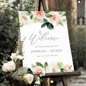 May include: A wedding welcome sign with a floral design featuring pink and white flowers. The sign reads "Welcome to the wedding of Jordan + Henry, August 23, 2020, New York".