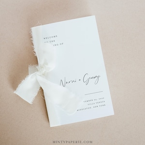 以下が含まれることがあります： ナルミ + ジョージの結婚式プログラム。白い紙に「ナルミ + ジョージの結婚式へようこそ」という文字と、2020年9月13日、ヴィラ・ヴェネツィア、ミドルタウン、ニューヨークの場所が書かれています。