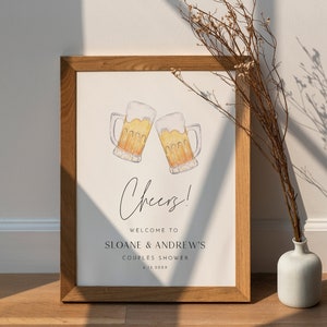 Peut inclure: Une affiche imprimable avec une illustration aquarelle de deux chopes de bière qui trinquent. L'affiche dit "Cheers!" et "Bienvenue à Sloane & Andrew's Couples Shower 6.13.20XX".