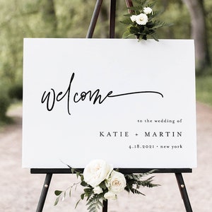 May include: White welcome sign with black calligraphy text on an easel. The sign reads "Welcome" to the wedding of Katie + Martin 4.18.2021 - New York.