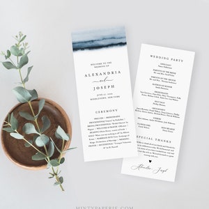 May include: Wedding program with a blue watercolour design. The program features the names Alexandria and Joseph, the wedding date, and ceremony details. A separate card lists the wedding party.