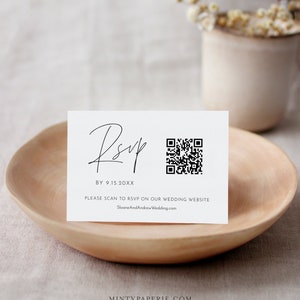 May include: A white RSVP card with black text and a black and white QR code. The text reads "RSVP BY 9.15.20XX PLEASE SCAN TO RSVP ON OUR WEDDING WEBSITE SloaneAndAndrewWedding.com"