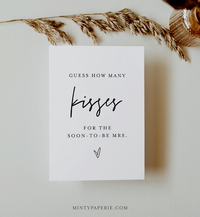 May include: White card with black text that reads "Guess how many kisses for the soon-to-be Mrs." with a small heart symbol at the bottom. The text "MintyPaperie.com" is at the bottom of the card.