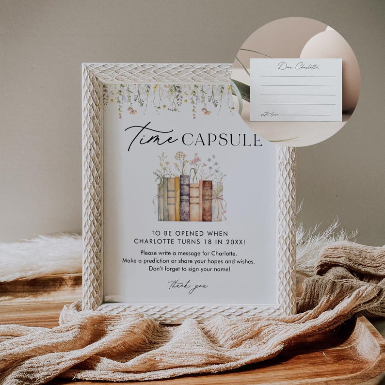 May include: White frame with a white mat and a printed sign that says "Time Capsule" with a stack of books and flowers. The sign says "To be opened when Charlotte turns 18 in 20XX!" and "Please write a message for Charlotte. Make a prediction or share your hopes and wishes. Don't forget to sign your name! Thank you."