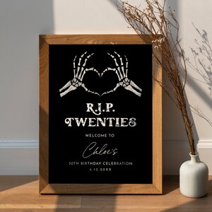 May include: A black and white sign with a skeleton hand making a heart shape. The sign reads "R.I.P. TWENTIES Welcome to Chloe's 30th Birthday Celebration 6.13.20XX".
